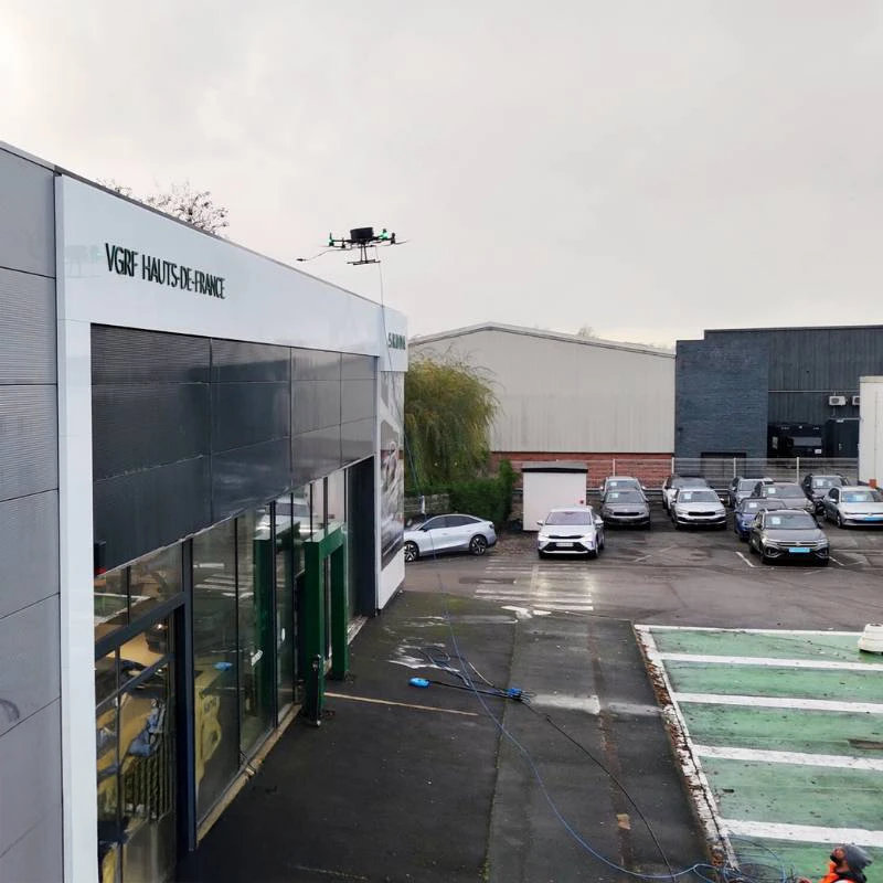 Scène extérieure d'un centre automobile avec drone en vol au-dessus du parking
