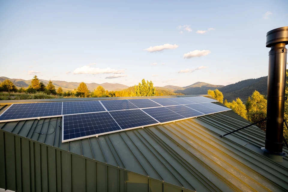 Panneaux solaires sur le toit d'une maison dans les montagnes au coucher du soleil