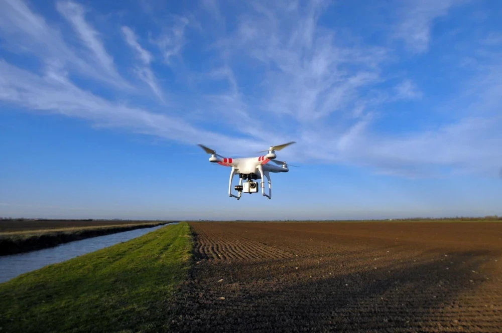 Homme accroupi sur piste d'aéroport surveillant drone professionnel au sol par temps ensoleillé