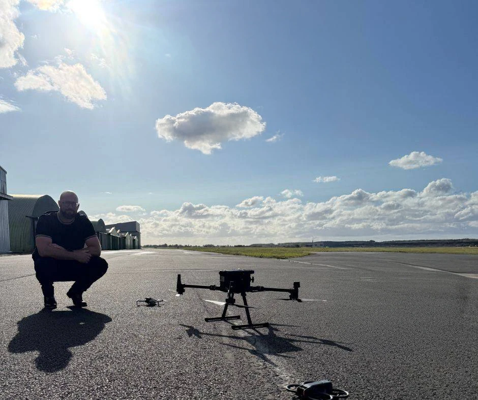 Scène extérieure : ouvrier en équipement de sécurité orange effectue le nettoyage haute pression d'une toiture de maison résidentielle