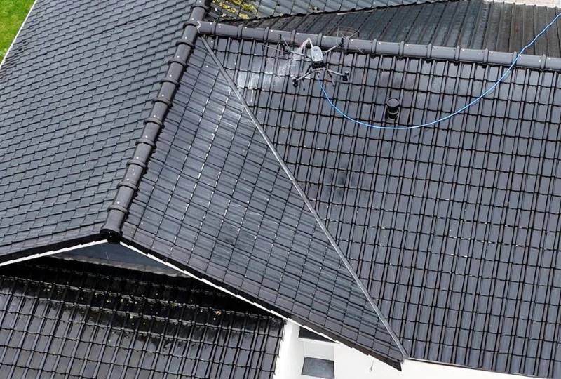 Main tenant un pulvérisateur à gâchette bleu et rouge diffuse un produit nettoyant sur surface brillante avec éponge jaune